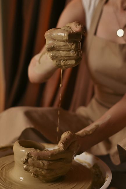 Hands shaping wet clay on a pottery wheel